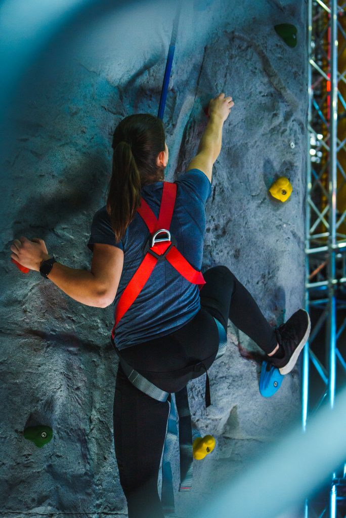 Frau klettert an einer Kletterwand bei Jumpin Warrior