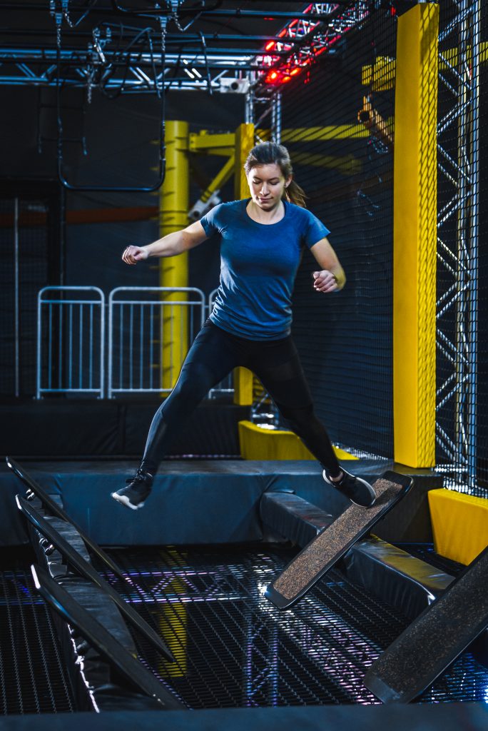 Frau bewältigt ein Balance-Hindernis im Ninja Warrior Parcours bei Jumpin Warrior