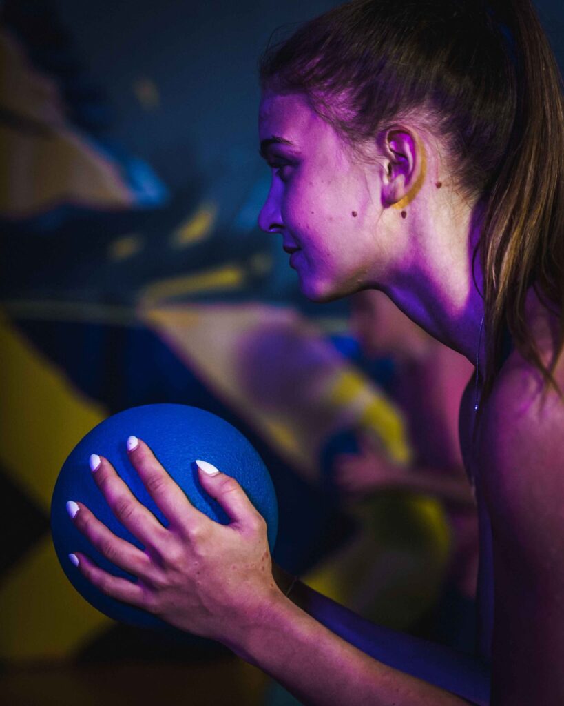 Frau mit blauem Ball in der Dodgeball Arena im Jumpin Warrior Park SCS Vösendorf