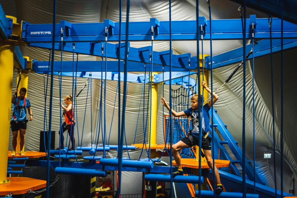 Kinder und Erwachsene in Hochseilgarten des Jumpin Warrior Indoor Abenteuerparks title: Hochseilgarten im Jumpin Warrior Abenteuerpark